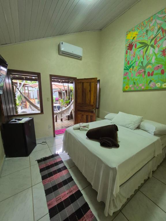 a bedroom with a bed with a black pillow on it at Pousada Casa Rosa in Itacaré