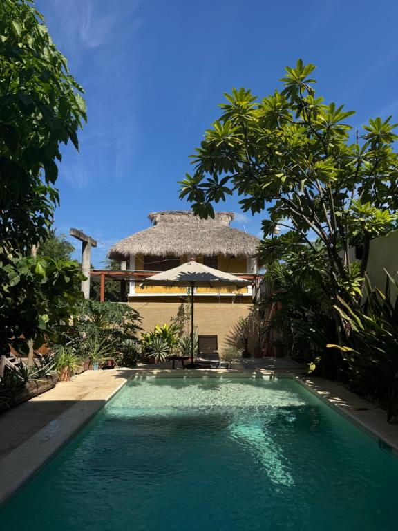 a swimming pool in front of a house with an umbrella at Casa Madre Selva in Brisas de Zicatela