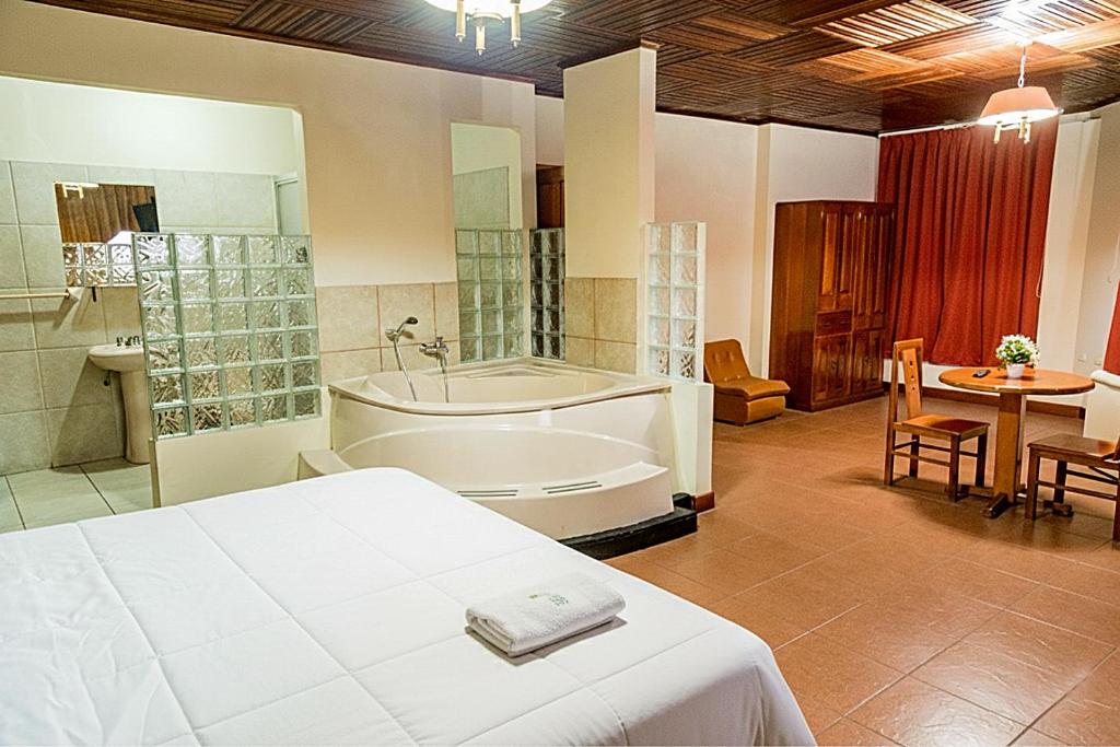 a bedroom with a bed and a tub and a table at Hotel Oro Verde Iquitos in Iquitos