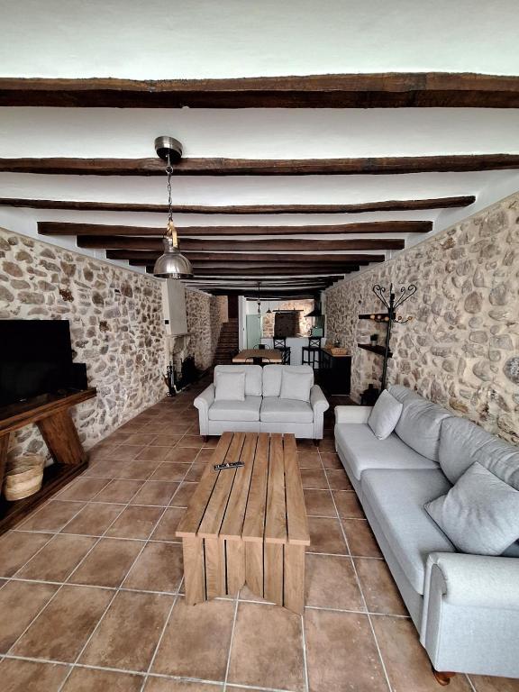 a living room with white furniture and a stone wall at Casa Trilles in Azuébar