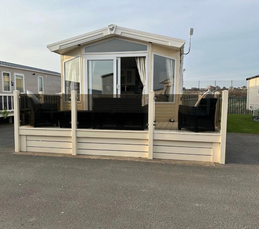 a screened in porch with chairs on a house at Caravan by the beach in Kinmel Bay