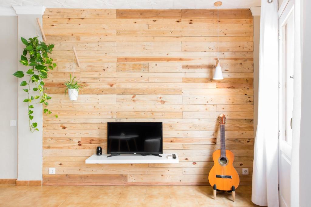 a room with a wooden wall with a television and a guitar at Ca'n Tosca Jávea in Jávea