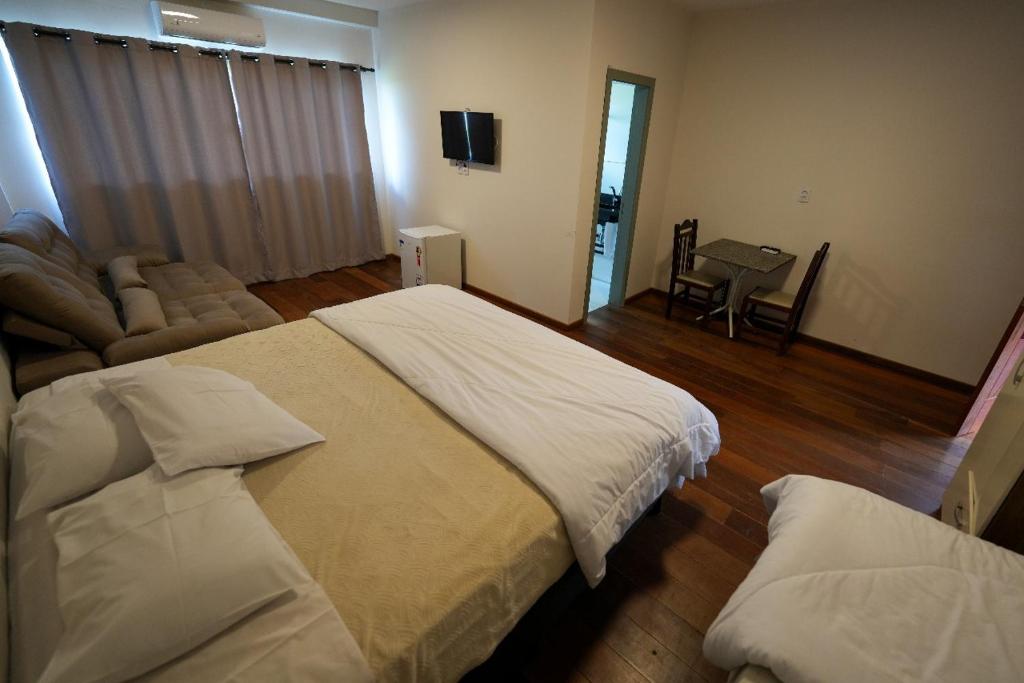 a bedroom with a large bed and a living room at Hotel Pedra Moura in Vacaria