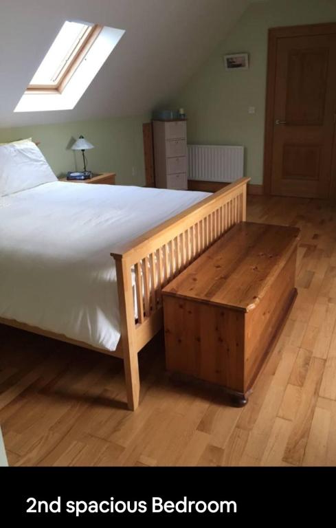 a bedroom with a large bed with a wooden foot board at Curraghchase Cottage in Limerick