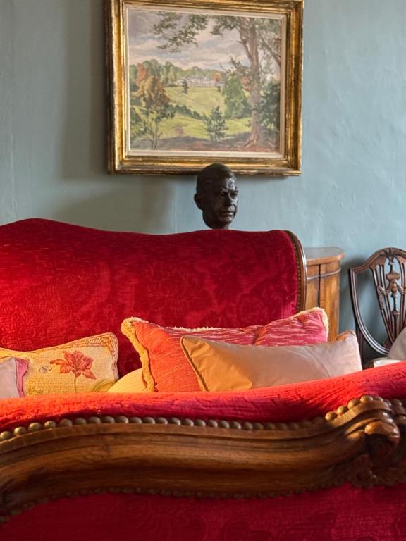 Un dormitorio con un sofá rojo con almohadas. en L Epernon, en Alençon