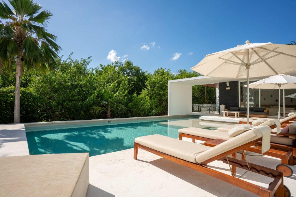 a swimming pool with lounge chairs and an umbrella at Villa Marazul 5BR Beach & Golf Access in Cancún
