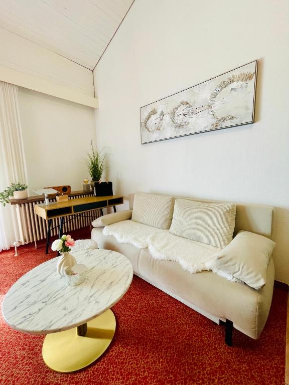 a living room with a couch and a table at Das CLASSIQUE Galerieappartement 50qm - Elegant und geräumig wohnen - Espressomaschine, Airfryer, Balkon, Vierbeinerfreundlich, Parkgarage -AppHaus Poseidon in Bad Griesbach
