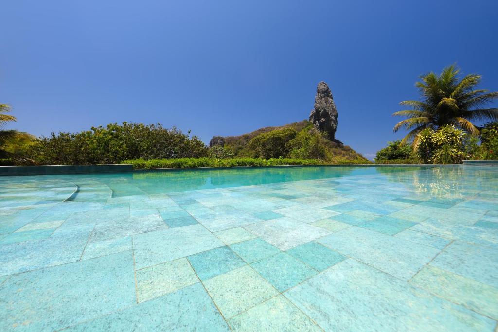 a swimming pool with an island in the background at Pousada Zé Maria in Fernando de Noronha