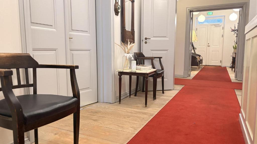 a hallway with two chairs and a red rug at Brodremenighedens Hotel, BW Signature Collection in Christiansfeld
