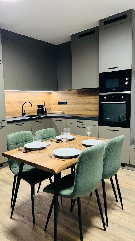 a kitchen with a wooden table with four chairs at SERENITAS Apartment RIVA PARK in Dunajská Streda