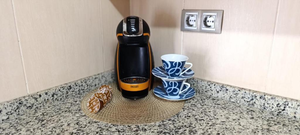a hair drier and two cups on a counter at Alojamiento en reforma in Alcalá de Guadaira