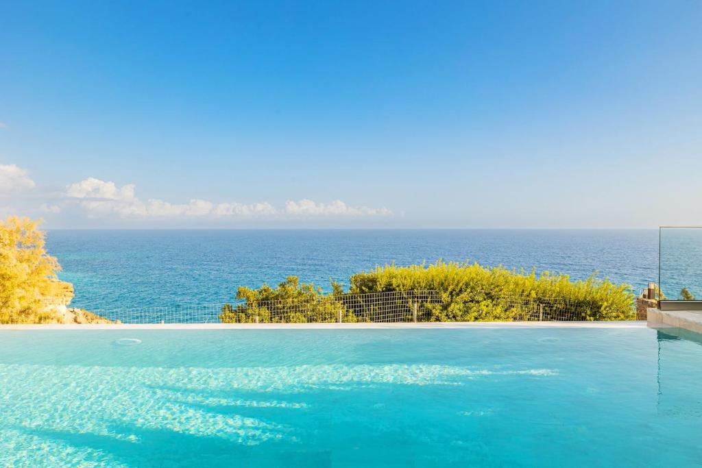 a swimming pool with the ocean in the background at Villa Anatoli in Achlia