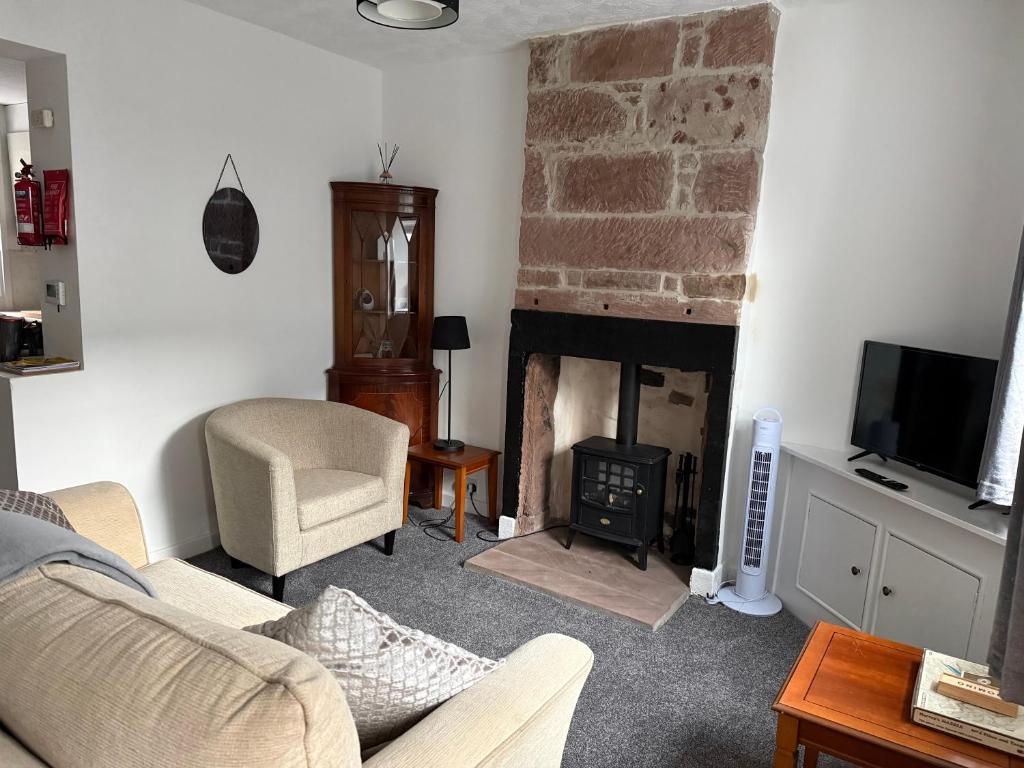 a living room with a fireplace with a couch and a chair at 17 Main Street in St Bees
