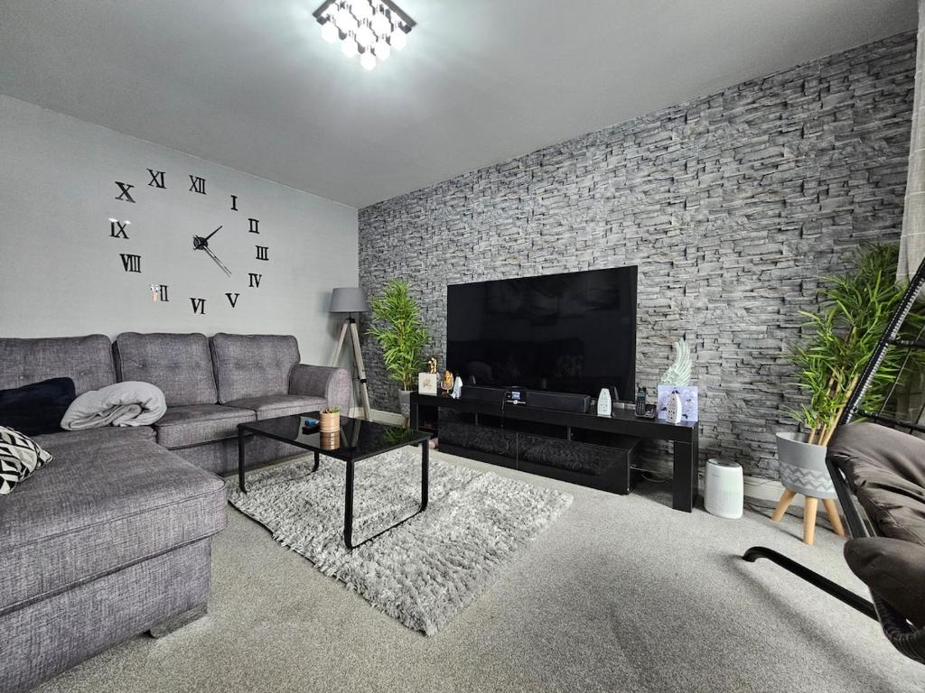 a living room with a brick wall with a large television at Modern spacious Home in Rhyl in Rhyl