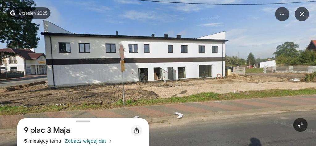 a white building on the side of a street at Motel Żabka in Łyse