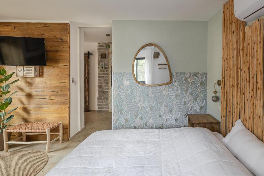 a bedroom with a large bed and a mirror at אי שם בגולן in Keshet