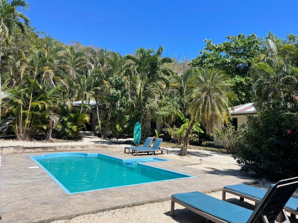 a swimming pool with two lounge chairs next to a house at Koba Apartments Santa Teresa in Santa Teresa Beach