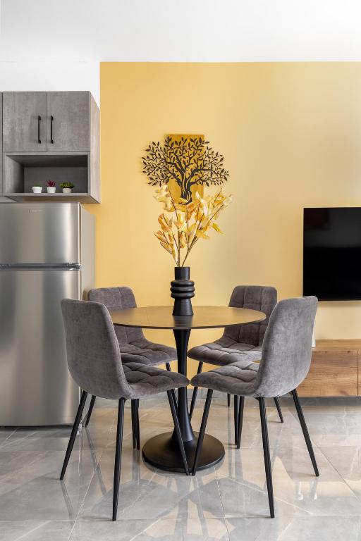 a dining room table with chairs and a vase with a plant at Anatoli Urban Apartment with private parking in Xanthi