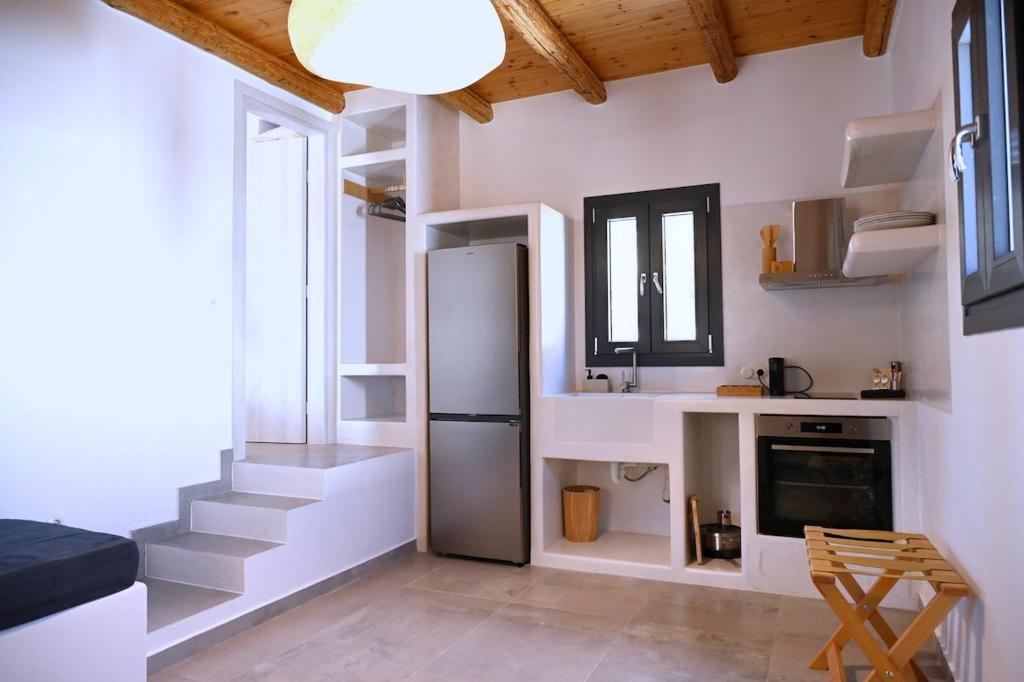 a kitchen with a refrigerator and stairs in a room at Alkyoni Celeste Kythnos in Kithnos