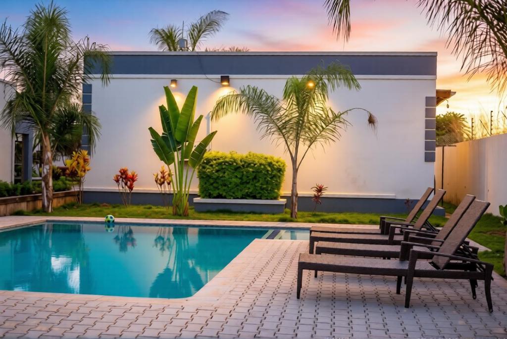 a swimming pool with two chairs next to a house at Muka Staytel in Ndola