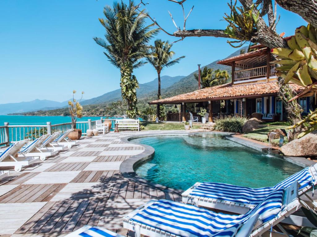 a pool at a resort with lounge chairs at Vilatoro Guest House in Ilhabela