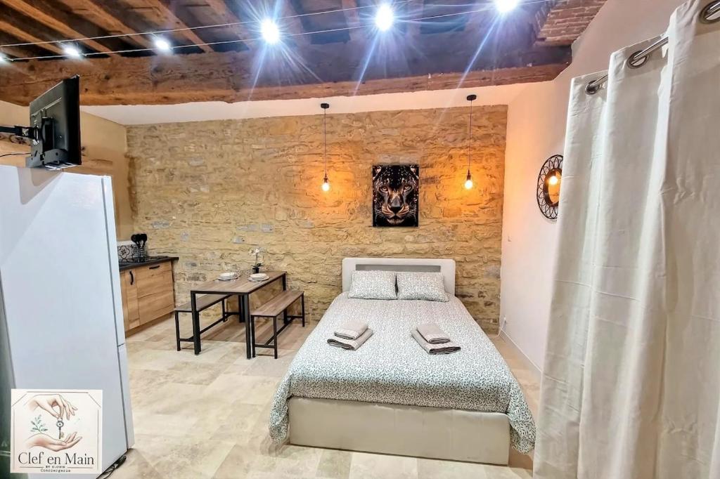 a bedroom with a bed and a table in a room at Le Petit Cocon Cozy studio proche de Lyon in Couzon-au-Mont-dʼOr