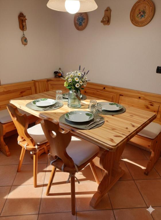 a wooden table with chairs and a vase of flowers at Lo chalet di Lucky in Campodolcino