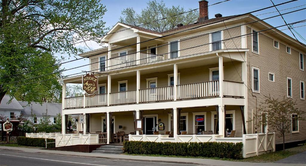 a large building with a balcony on a street at Auberge Ayer's Cliff in Ayers Cliff