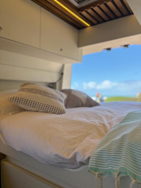 a bed with two pillows on top of it at Van aménagé tout confort in Tamaris