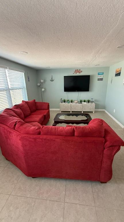 a red couch in a living room with a tv at Modern 3BR Home in secure neighborhood with Free Parking & WiFi in Riverview