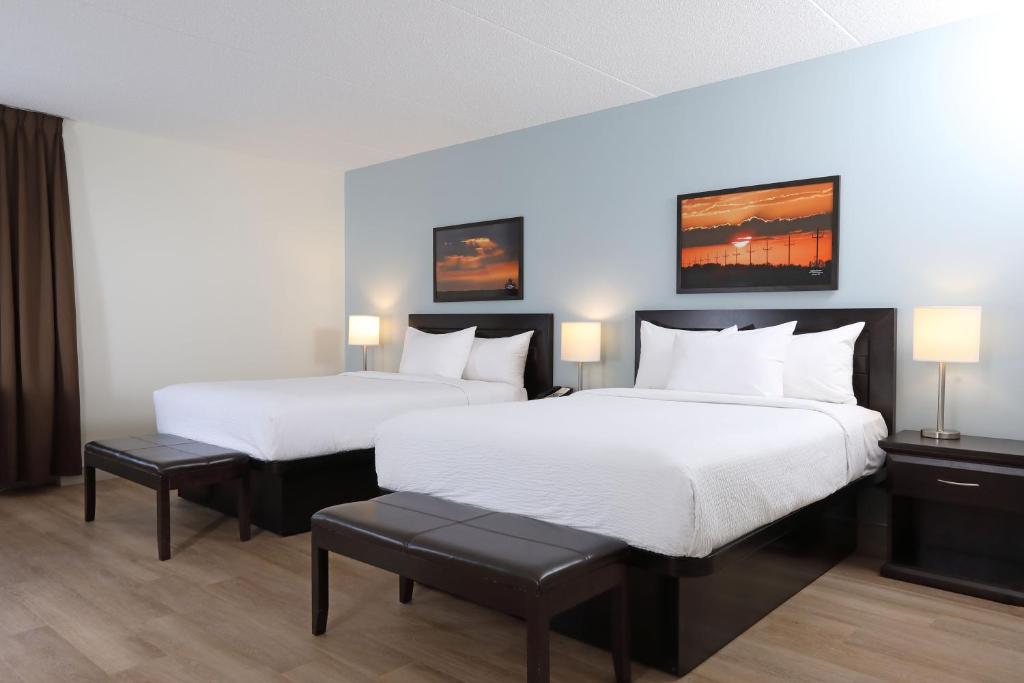 two beds in a hotel room with white sheets at Canad Inns Health Sciences Centre in Winnipeg