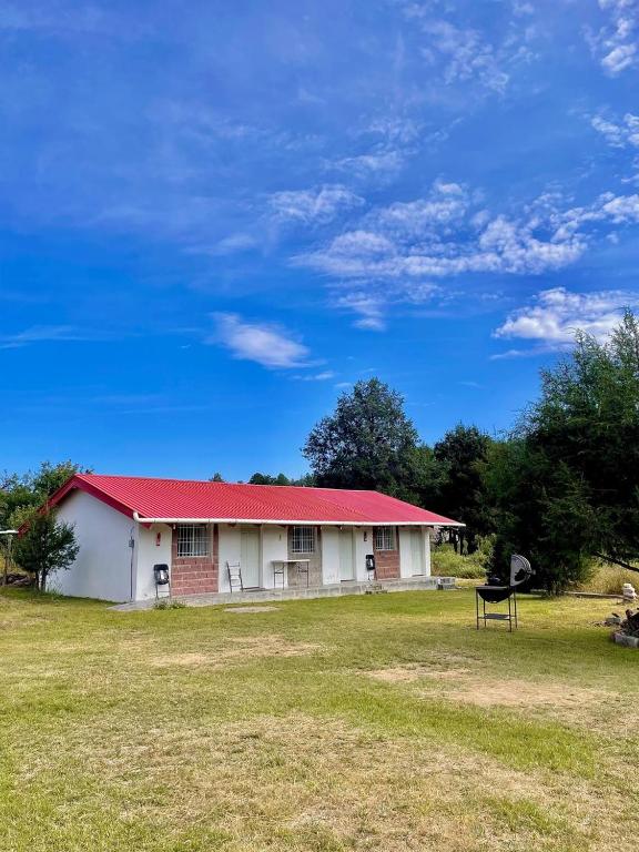 a white building with a red roof in a field at Hotel Mi Lindo Chihuahua in Areponapuchi