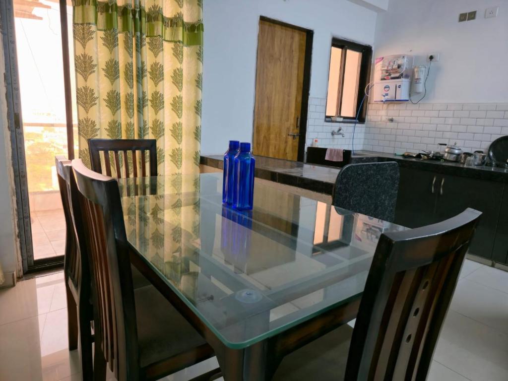 a glass table in a kitchen with two chairs at 1 Bhk Mayra Homes in Raipur