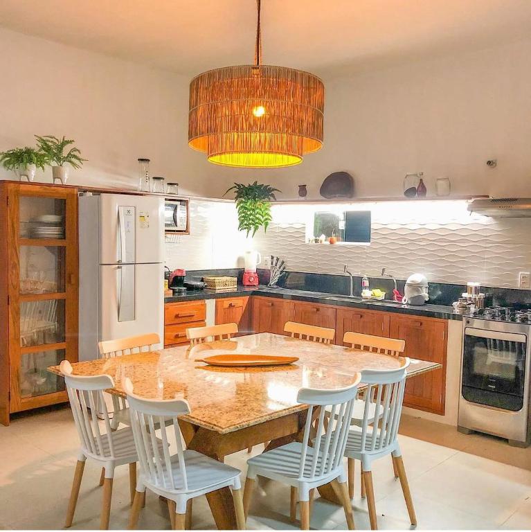 a kitchen with a table and chairs and a refrigerator at Chalé Pitanga in Pôrto de Pedras