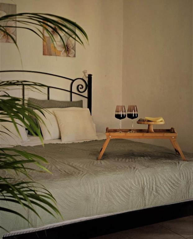 a bed with two glasses of wine on a table at Pavlos Maria studios in Skiathos