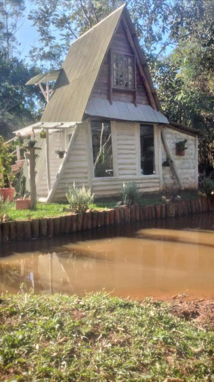 a small house with a roof over a pond at Chalé Do Lago in Piracaia