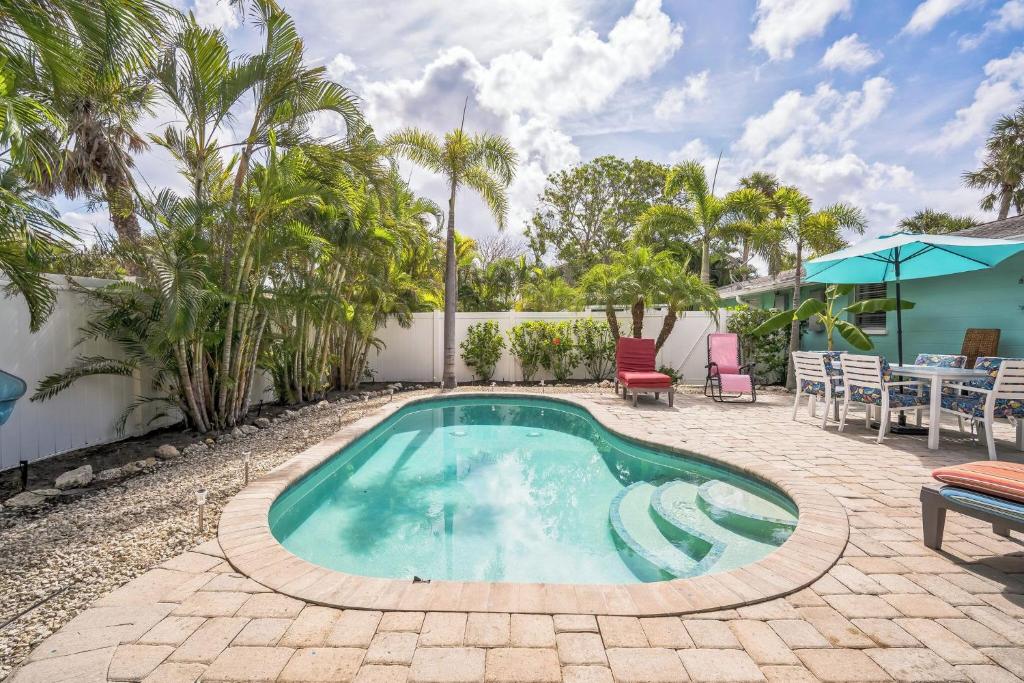 a swimming pool with a patio with a table and chairs at pink peacock in Holmes Beach