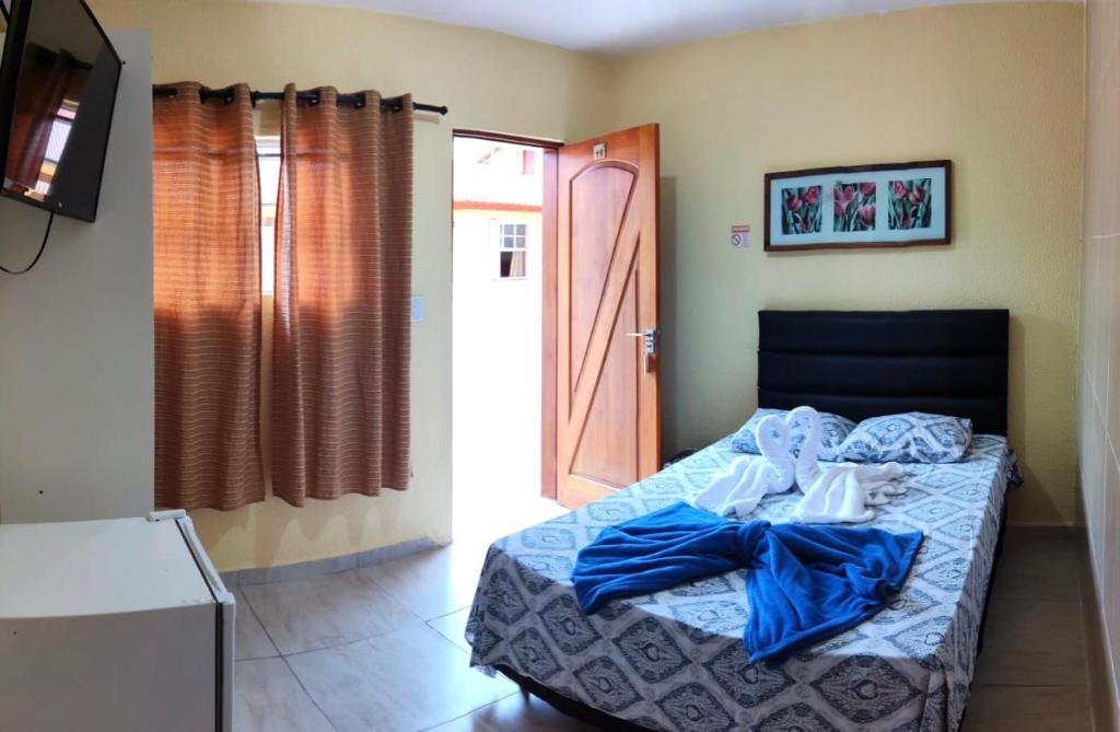 a bedroom with a bed with blue sheets and an open door at Hotel Leblon in Peruíbe