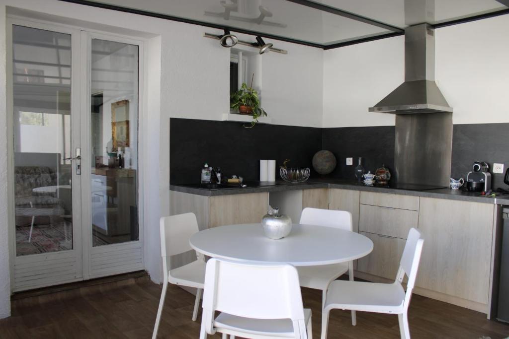 a kitchen with a white table and white chairs at Villa Danemark in Colombes