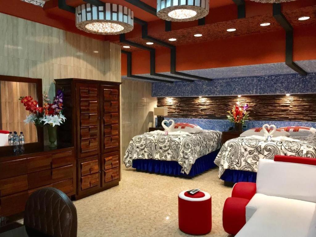 two beds in a room with red and blue at Hotel La Cabaña in Ciudad Melchor de Mencos