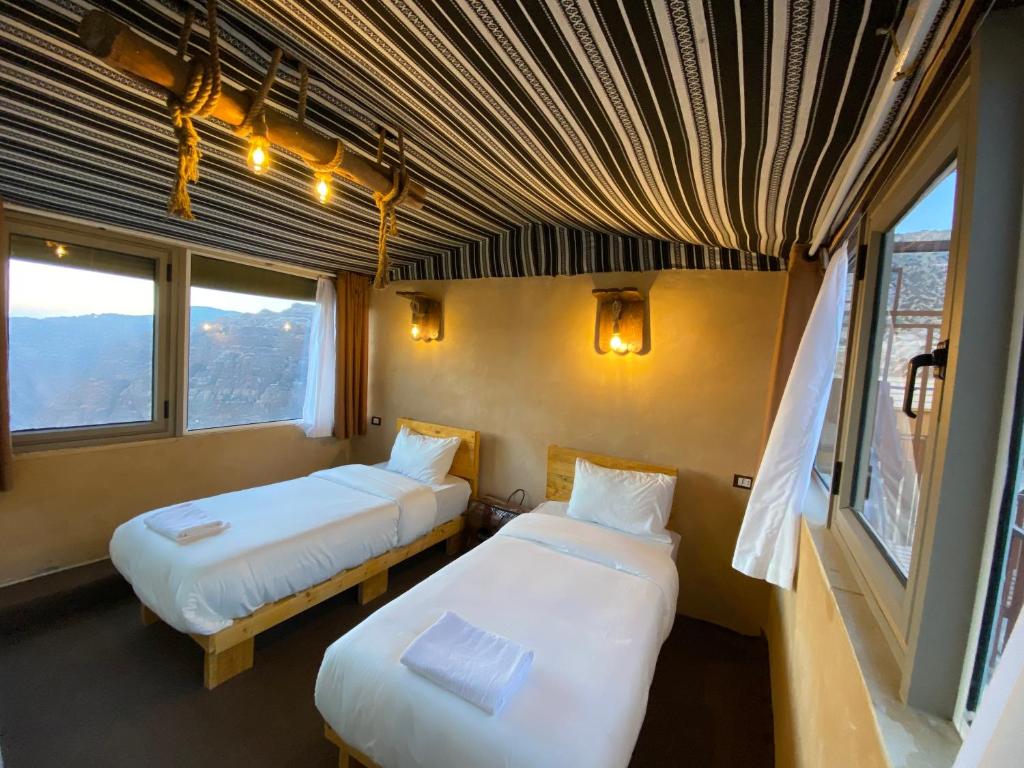 two beds in a room with two windows at Dana Trail Nomad Camp in Dana