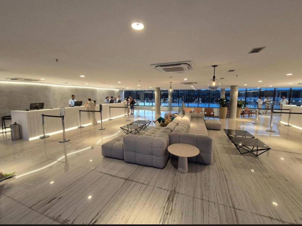 a lobby with couches and tables and people in a building at Porto 2 live in Porto De Galinhas