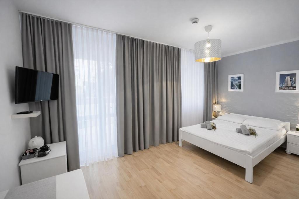 a white bedroom with a bed and a tv at Ośrodek TVP in Ciechocinek