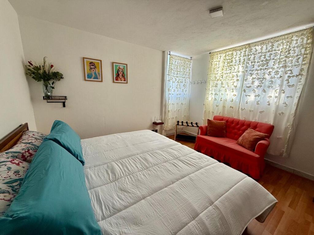 a bedroom with a bed and a red chair at Departamento acogedor, moderno y céntrico in Apizaco