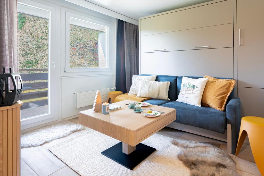 a living room with a blue couch and a coffee table at Studio MORGINS avec piscine Gratuite in Morgins