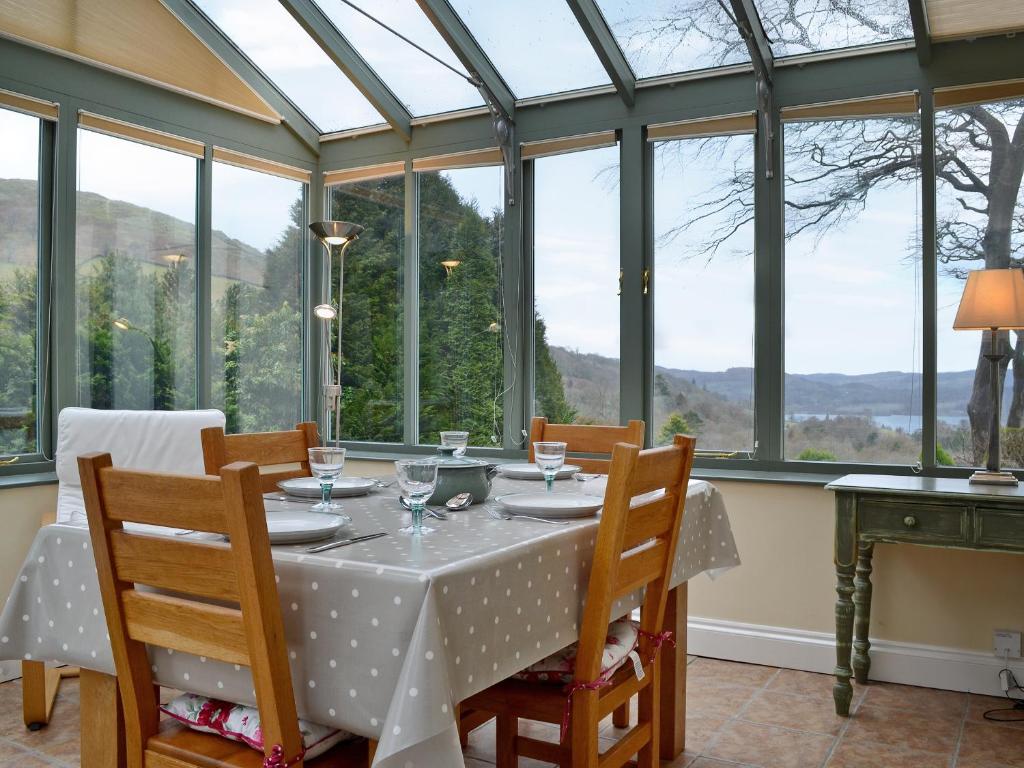a dining room with a table with chairs and windows at Fellmere in Ambleside