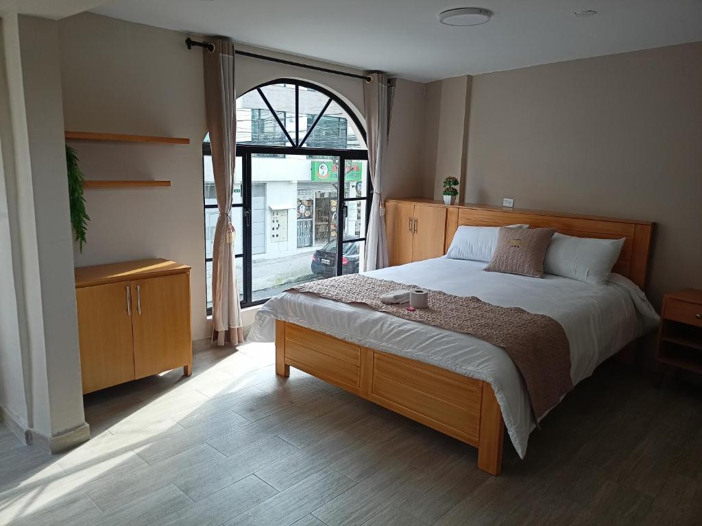 a bedroom with a large bed and a large window at Hostal Tayupanda in Quito