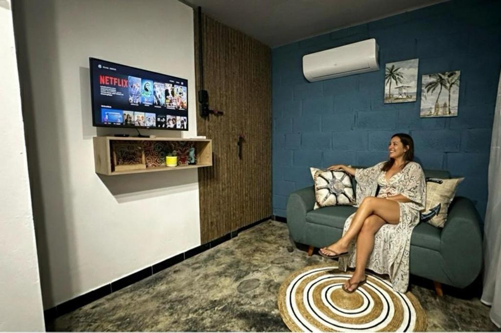 a woman sitting on a couch watching a tv at Cabaña la Industrial in Coveñas