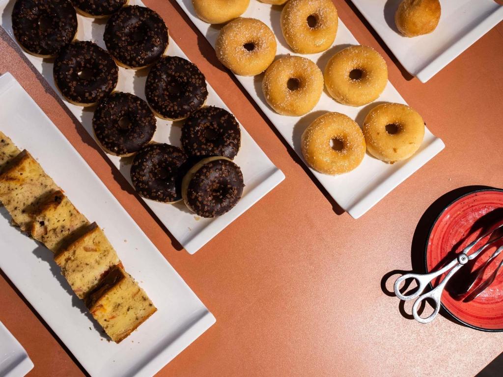 A close-up of breakfast pastries and doughnuts arranged on white serving platters.