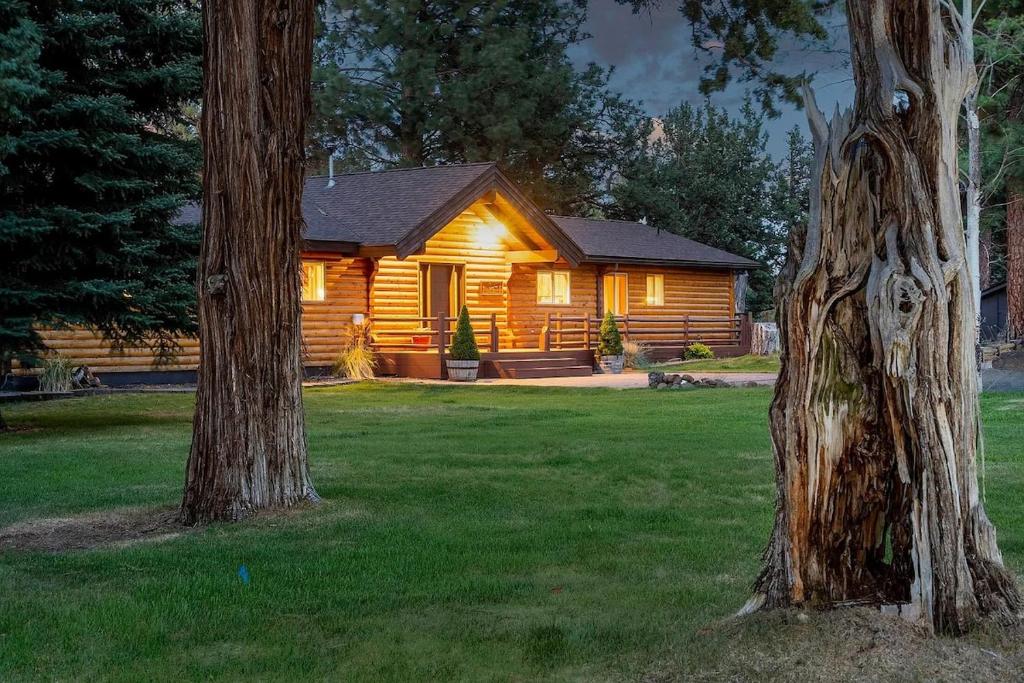a log cabin in a yard with two trees at Sisters Cabin in Sisters